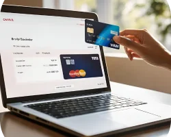 Main tenant une carte bancaire devant un ordinateur affichant une interface de paiement en ligne